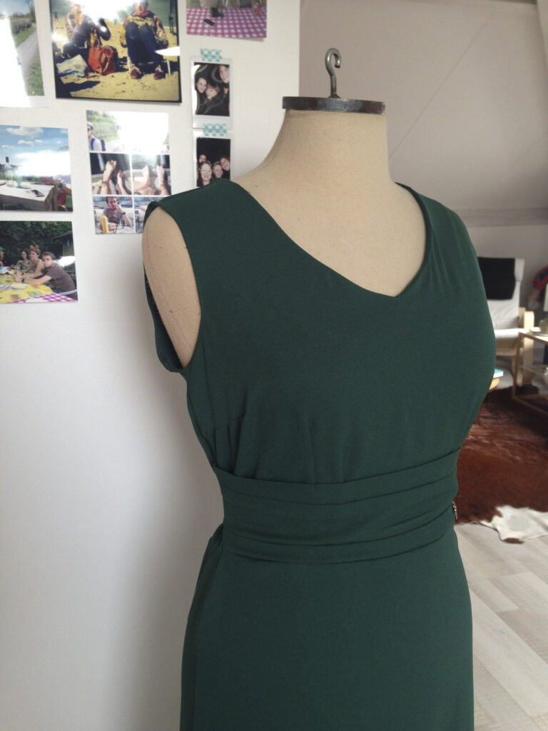 Groene jurk na retouches door Curieus Retouches Begijnendijk, zonder mouwen en met bredere halsuitsnijding, klaar voor feestjes.