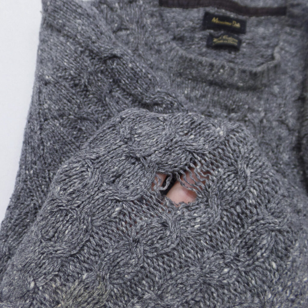 Wollen trui van Ward bij Curieus Retouches Begijnendijk, met een klein gat in de mouw klaar voor een onzichtbare herstelling.